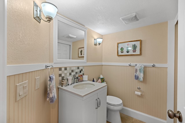 bathroom with vanity, a textured ceiling, decorative backsplash, tile patterned flooring, and toilet