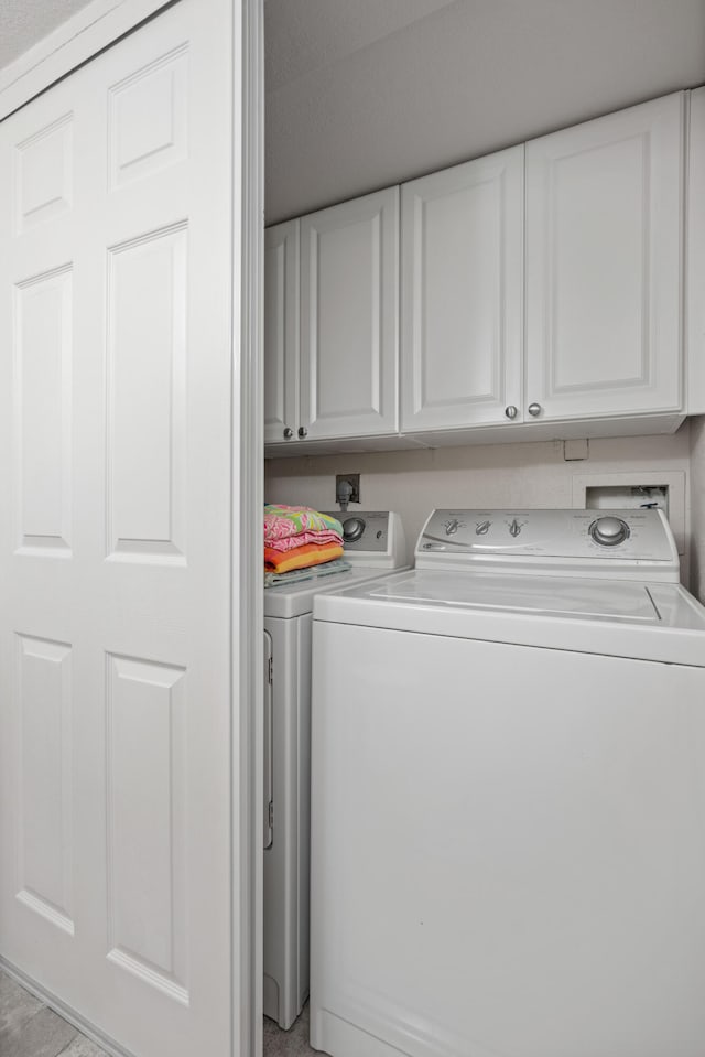 laundry area with separate washer and dryer and cabinets