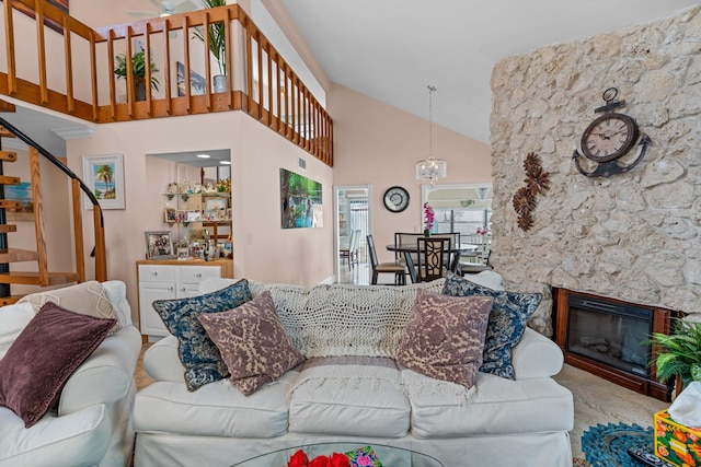 living room featuring high vaulted ceiling, ceiling fan with notable chandelier, and a fireplace