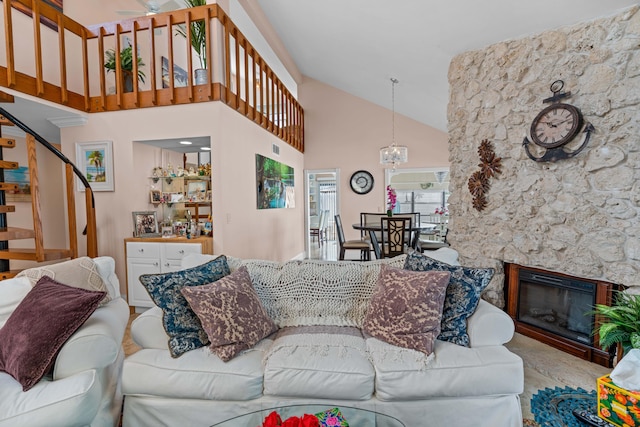 living room featuring a notable chandelier, high vaulted ceiling, a fireplace, and stairs