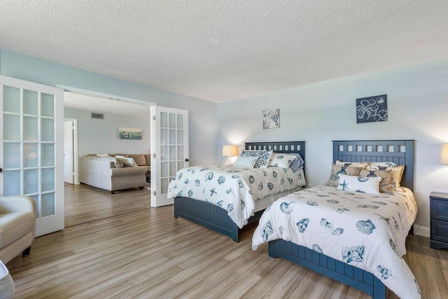 bedroom with wood-type flooring, french doors, and a textured ceiling