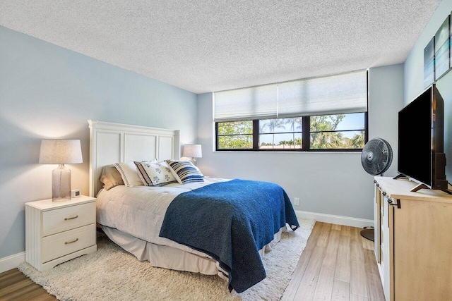 bedroom with a textured ceiling and light wood-type flooring