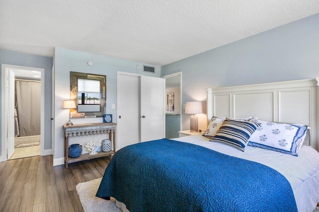 bedroom with a textured ceiling, hardwood / wood-style floors, and ensuite bath