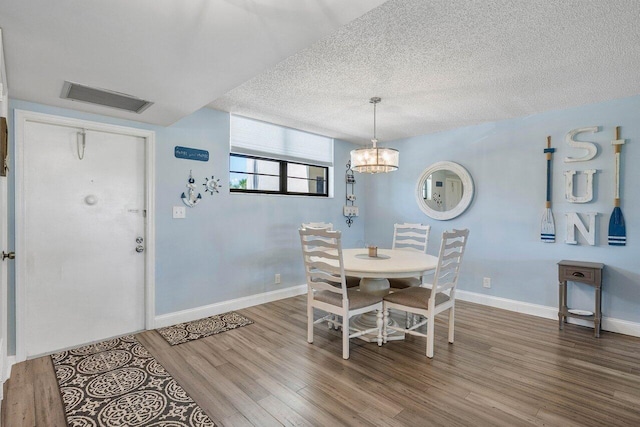 dining area featuring an inviting chandelier, wood-type flooring, and a textured ceiling