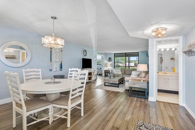 dining space featuring hardwood / wood-style flooring, a textured ceiling, and an inviting chandelier