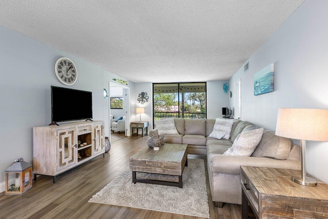 living room featuring dark wood-type flooring, a textured ceiling, and floor to ceiling windows