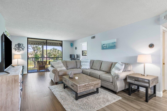 living room featuring light hardwood / wood-style floors, a textured ceiling, and floor to ceiling windows