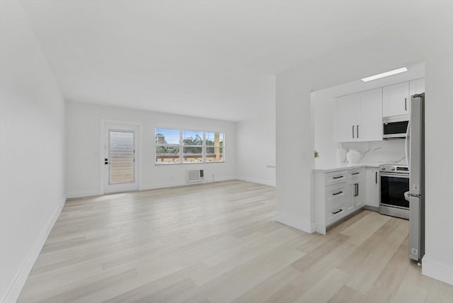 kitchen with backsplash, appliances with stainless steel finishes, light hardwood / wood-style floors, and white cabinets