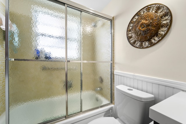 bathroom featuring toilet and bath / shower combo with glass door