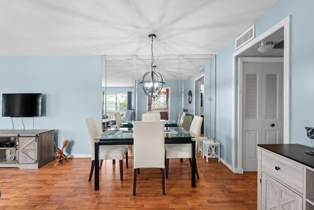 dining space featuring a textured ceiling, a notable chandelier, and light hardwood / wood-style floors