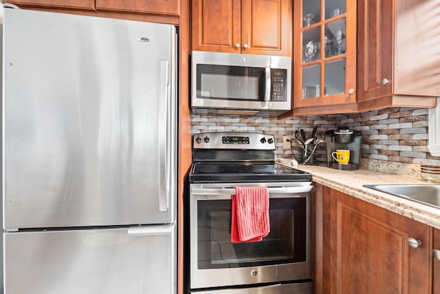 kitchen featuring light stone counters, decorative backsplash, and appliances with stainless steel finishes