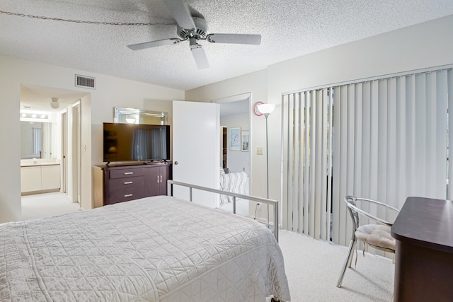 bedroom featuring a textured ceiling, light carpet, ceiling fan, and ensuite bathroom