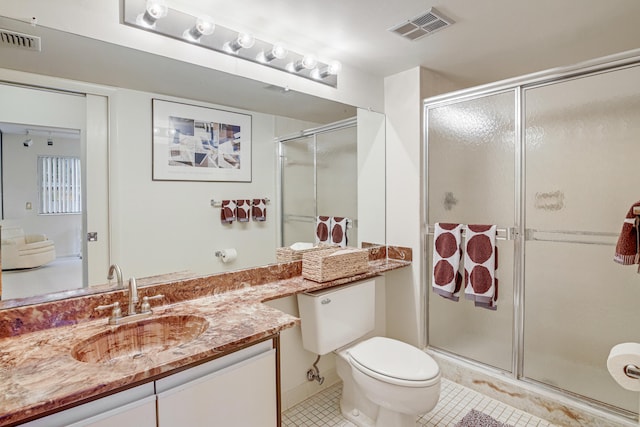 bathroom with toilet, tile patterned floors, vanity, and a shower with door