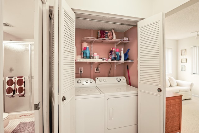 washroom with washing machine and clothes dryer, a textured ceiling, and carpet floors