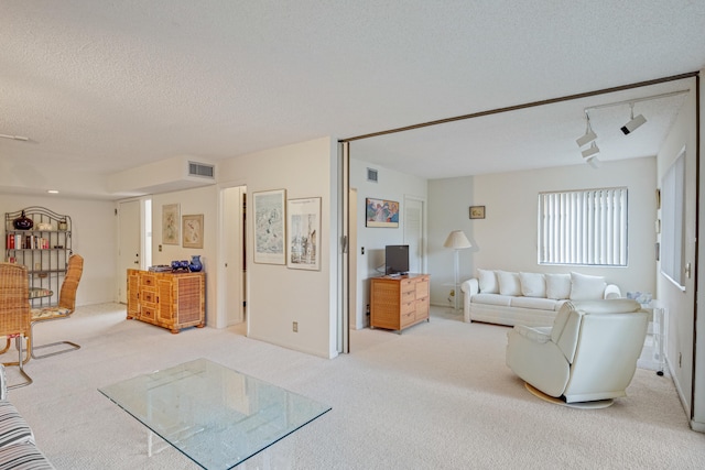 living room with light colored carpet, rail lighting, and a textured ceiling