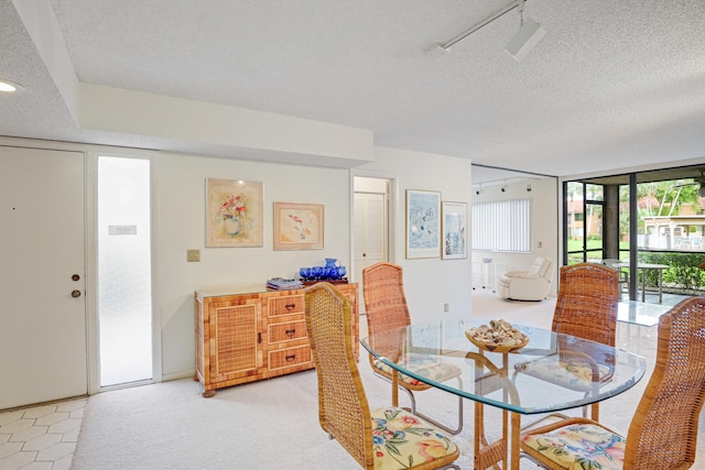 dining area featuring rail lighting, light carpet, and a textured ceiling