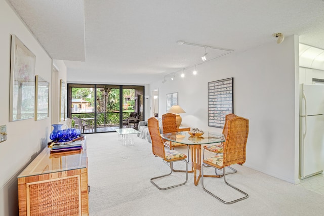 dining area featuring a textured ceiling, light carpet, and rail lighting