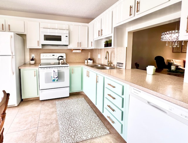 kitchen with white appliances, sink, light tile patterned floors, an inviting chandelier, and white cabinets