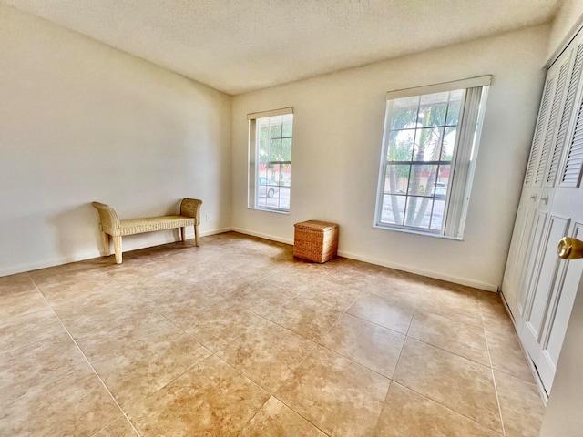 unfurnished room featuring light tile patterned flooring, a healthy amount of sunlight, and a textured ceiling