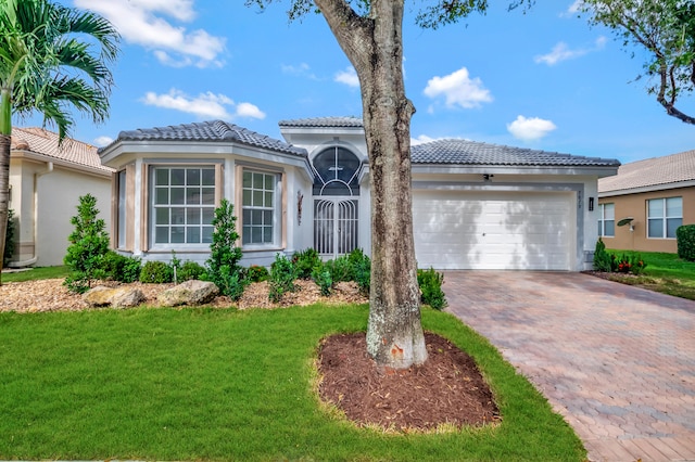 mediterranean / spanish home with a garage and a front lawn