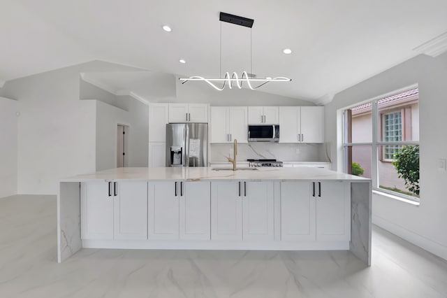 kitchen featuring white cabinets, decorative light fixtures, a large island with sink, and appliances with stainless steel finishes