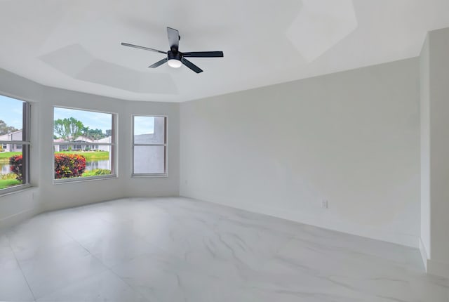 spare room with plenty of natural light, ceiling fan, and a raised ceiling