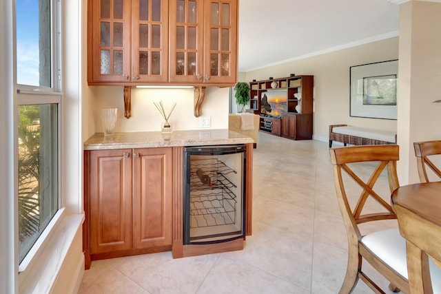 bar featuring light tile patterned flooring, light stone counters, ornamental molding, and beverage cooler