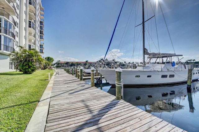 view of dock with a lawn and a water view