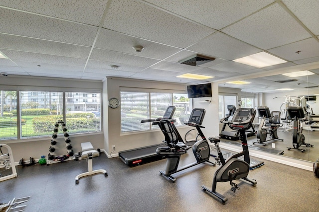 exercise room featuring a paneled ceiling and plenty of natural light