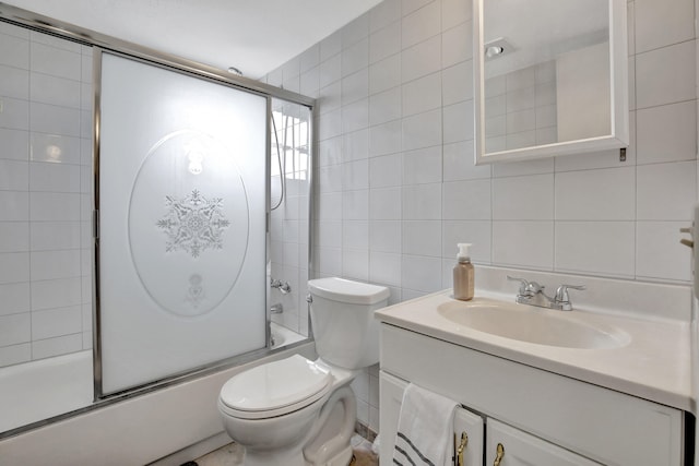 full bathroom featuring tile walls, vanity, combined bath / shower with glass door, and toilet