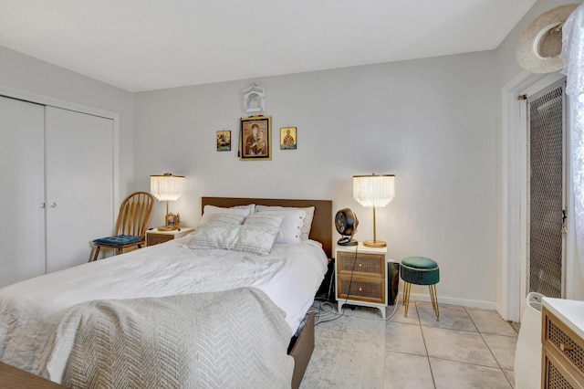 bedroom with light tile patterned floors, a closet, and baseboards