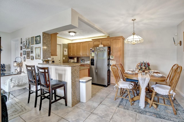 kitchen featuring stainless steel fridge with ice dispenser, a peninsula, a breakfast bar, light tile patterned floors, and hanging light fixtures