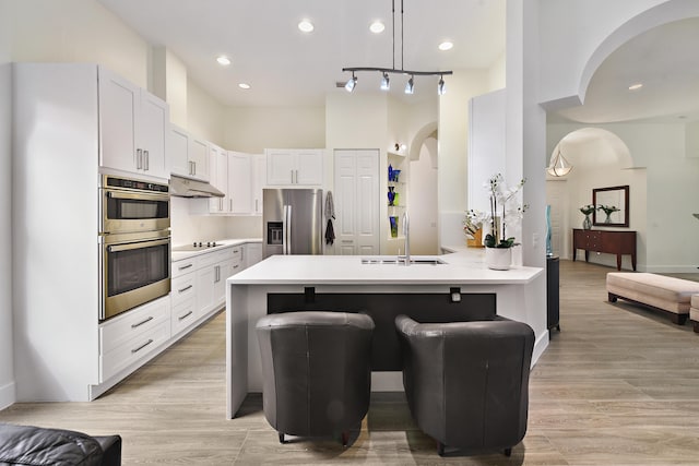 kitchen with stainless steel appliances, white cabinetry, a breakfast bar, kitchen peninsula, and light hardwood / wood-style flooring