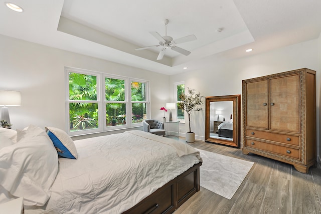 bedroom featuring hardwood / wood-style flooring, ceiling fan, and a raised ceiling