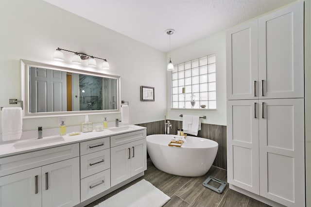 bathroom with wood-type flooring, vanity, separate shower and tub, and a textured ceiling