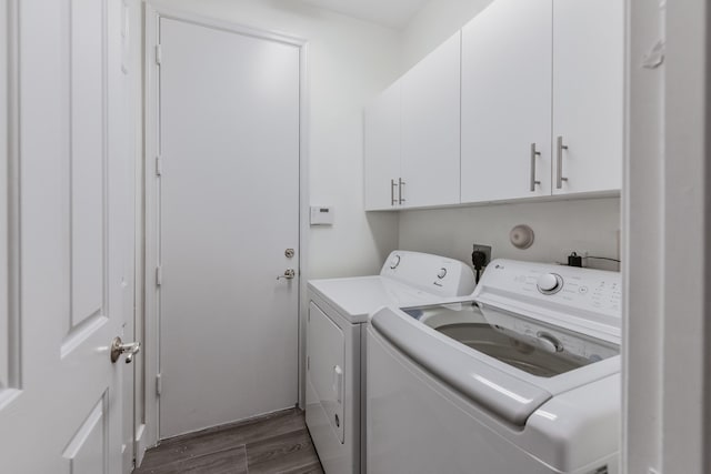 clothes washing area with separate washer and dryer, dark hardwood / wood-style flooring, and cabinets