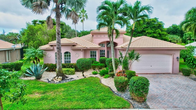 mediterranean / spanish house featuring a garage and a front lawn