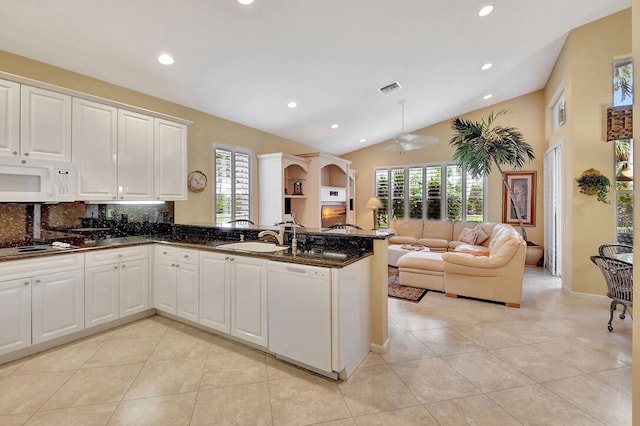 kitchen with kitchen peninsula, a healthy amount of sunlight, white appliances, and vaulted ceiling