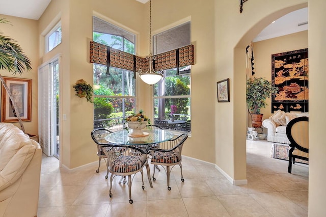 dining space featuring light tile patterned floors and a towering ceiling