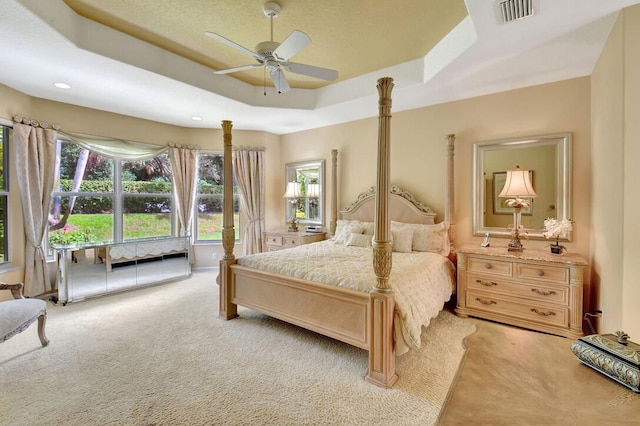 bedroom with light carpet, ceiling fan, and a raised ceiling