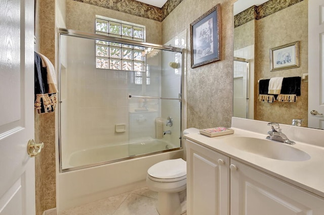 full bathroom with bath / shower combo with glass door, tile patterned flooring, vanity, and toilet