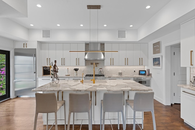 kitchen with hanging light fixtures, dark hardwood / wood-style flooring, white cabinetry, a kitchen island with sink, and stainless steel appliances