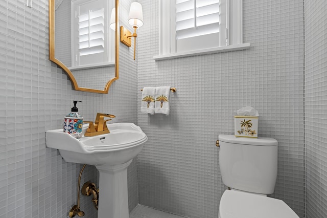 bathroom with toilet, tile walls, and plenty of natural light