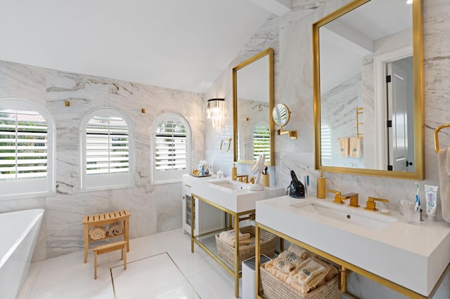 bathroom with a bathing tub, vanity, tile walls, and vaulted ceiling