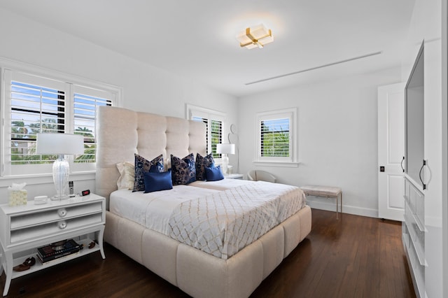 bedroom with multiple windows and dark hardwood / wood-style floors