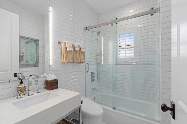 full bathroom featuring backsplash, vanity, shower / bath combination with glass door, and toilet