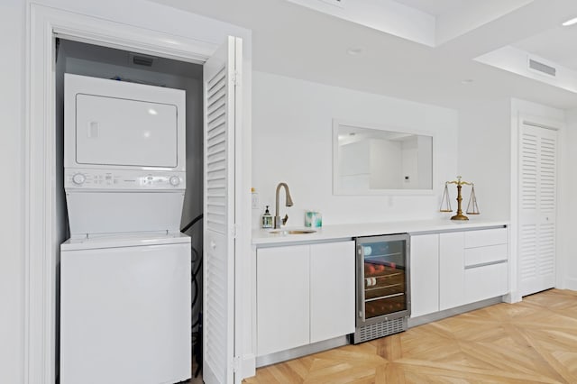 laundry room with wine cooler, light parquet flooring, stacked washer and dryer, and wet bar