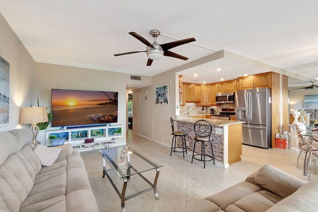 living room with ceiling fan, a textured ceiling, light tile patterned floors, and sink