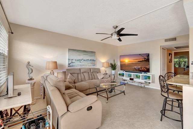 living room featuring ceiling fan, a textured ceiling, and light tile patterned floors