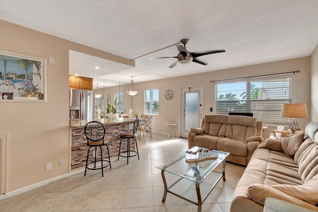 tiled living room featuring a wealth of natural light, a textured ceiling, and ceiling fan